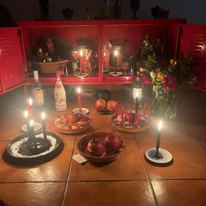 Assentamento com velas, flores, maçãs e bebidas diante do altar