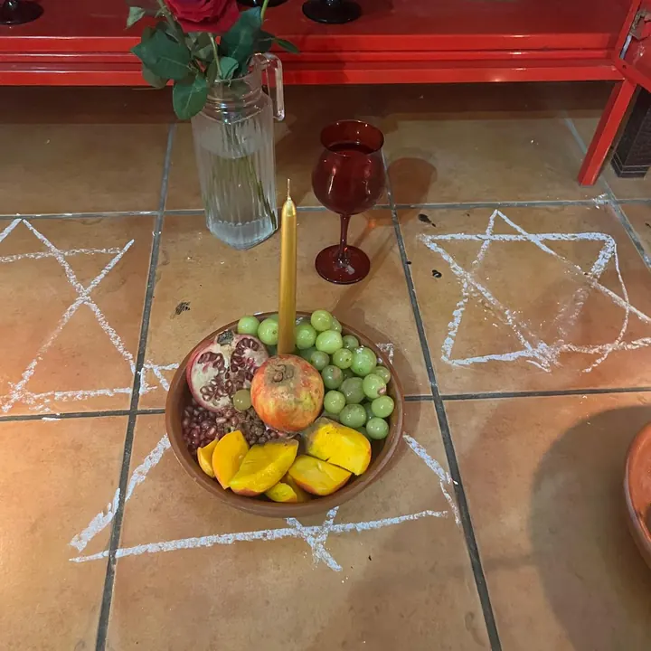 Oferenda de frutas com vela dourada, dentro de pontos riscados no chão